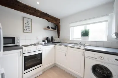 a kitchen with white cabinets and a washer and dryer at Colchester Town Duplex Apartment in Colchester