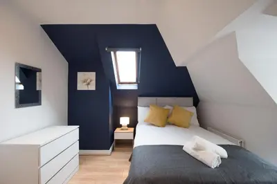 a bedroom with a bed and a blue wall at Colchester Town Duplex Apartment in Colchester