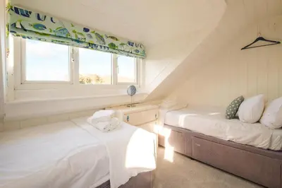 two beds in a room with a window at Shore Cote, Thorpeness in Thorpeness