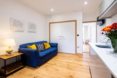 a living room with a blue couch and a table at Three Tuns Apartments - Ash in Pettistree