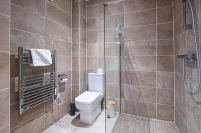 a bathroom with a toilet and a glass shower at Three Tuns Apartments - Ash in Pettistree