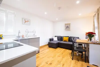 a kitchen and living room with a couch and a table at Three Tuns Apartments - Sycamore in Pettistree