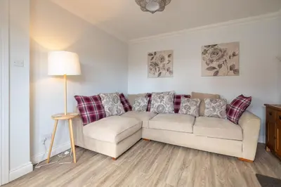 a living room with a couch and a lamp at Pigwig Cottage, Thorpeness in Thorpeness