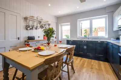 a kitchen with a wooden table with two glasses of wine at Elm Cottage in Aldeburgh