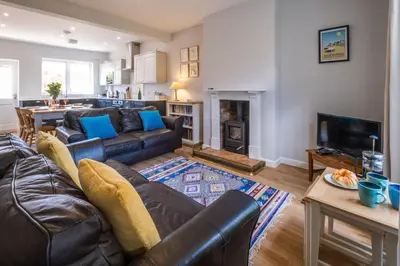 a living room with a leather couch and a table at Elm Cottage in Aldeburgh