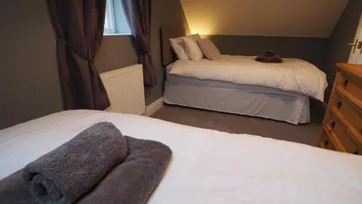 a bedroom with two beds with towels on them at Woodlands View in Halesworth