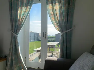 a bedroom with a sliding glass door with a picnic table outside at Hideaway Cottage in Halesworth