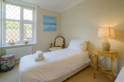 a bedroom with a bed with a lamp and a chair at Turret House, Thorpeness - Close to the beach, Thorpeness Lake , Thorpeness Hotel, Golf and Country Club - Aldeburgh Coastal Cottages in Thorpeness
