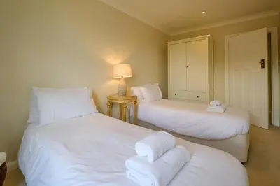 a room with two beds with white sheets and a lamp at Turret House, Thorpeness - Close to the beach, Thorpeness Lake , Thorpeness Hotel, Golf and Country Club - Aldeburgh Coastal Cottages in Thorpeness
