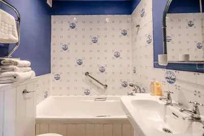 a blue and white bathroom with a tub and a sink at Margo's Cottage, Orford in Orford