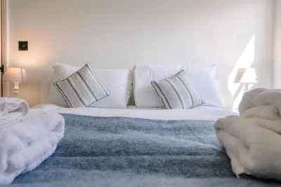 a bedroom with a bed with white sheets and pillows at Margo's Cottage, Orford in Orford