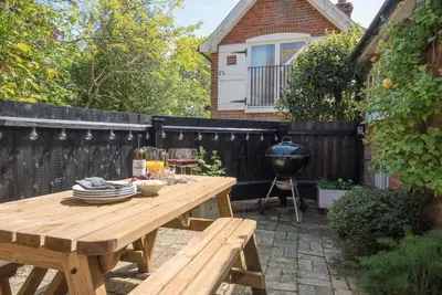 a wooden picnic table in a backyard with a grill at Margo's Cottage, Orford in Orford