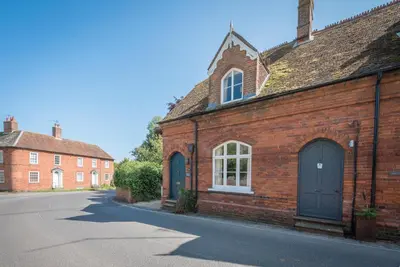 a brick building with blue doors on a street at Margo's Cottage, Orford in Orford