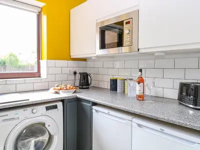 a kitchen with a washing machine and a microwave at Village Retreat in Ely