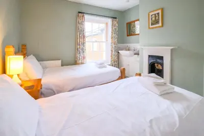 two beds in a room with a fireplace at 4 Old Homes, Thorpeness - Only a stones throw from the beach - Aldeburgh Coastal Cottages in Thorpeness