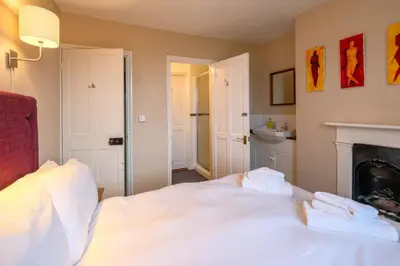 a bedroom with a white bed and a fireplace at 4 Old Homes, Thorpeness - Only a stones throw from the beach - Aldeburgh Coastal Cottages in Thorpeness