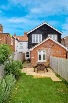 a brick house with a picnic table in the yard at 4 Old Homes, Thorpeness - Only a stones throw from the beach - Aldeburgh Coastal Cottages in Thorpeness