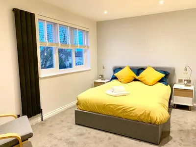 a bedroom with a bed with yellow pillows and a window at Stylish Cambridge Pad in Bar Hill