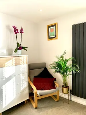 a living room with a chair and a plant at Stylish Cambridge Pad in Bar Hill