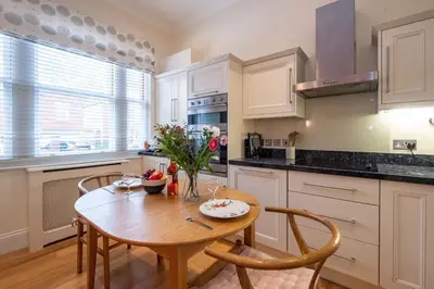 a kitchen with a wooden table and chairs in a kitchen at Polly's - Aldeburgh Coastal Cottages in Aldeburgh