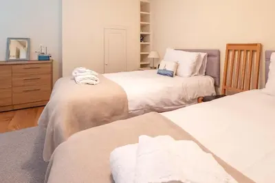 a bedroom with two beds and a dresser in it at Polly's - Aldeburgh Coastal Cottages in Aldeburgh