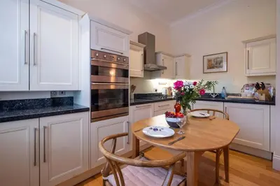 a kitchen with a wooden table and a table and chairs at Polly's - Aldeburgh Coastal Cottages in Aldeburgh