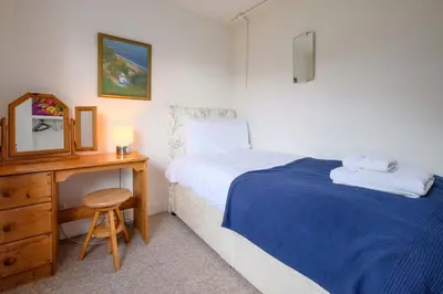 a bedroom with a bed and a desk with a mirror at Beaver Cottage in Aldeburgh