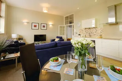 a living room with a table and a blue couch at Beachcomber - Aldeburgh Coastal Cottages in Aldeburgh
