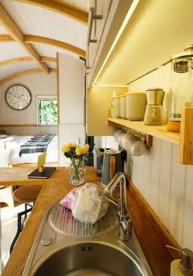 a kitchen with a sink and a kitchen with a bed at Piano Forte - a delightful rural shepherd hut & hot tub available ! in Rushford