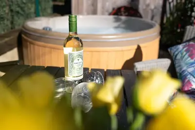 a bottle of wine sitting on a table next to a barrel at Piano Forte - a delightful rural shepherd hut & hot tub available ! in Rushford