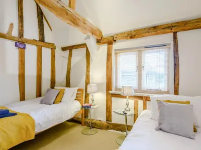 two beds in a room with wooden beams at Laurel Barn in Ashwellthorpe