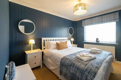 a bedroom with a bed and two mirrors on the wall at 69 Saxmundham Road in Aldeburgh