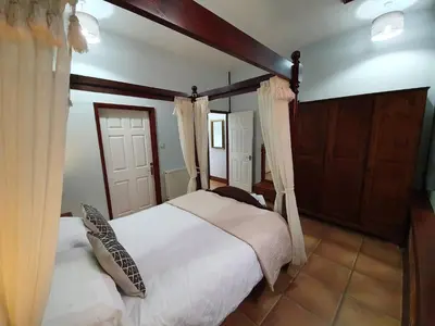 a bedroom with a bed with white sheets and curtains at Low Farm Cottages in Woodbridge