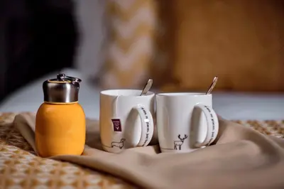 two coffee mugs and a bottle of mustard on a table at The Three Blackbirds in Stetchworth