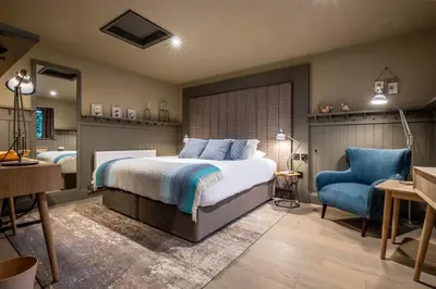 a bedroom with a bed and a blue chair at The Three Blackbirds in Stetchworth