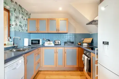 a kitchen with wooden cabinets and blue tiles at 1 Bed in Woodbridge oc-meb in Sudbourne