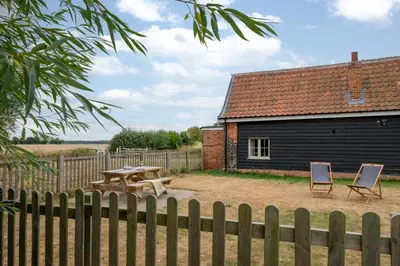a picnic table and two chairs in front of a building at 1 Bed in Ipswich oc-spha in Harkstead