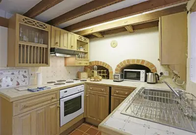 a kitchen with wooden cabinets and a stove top oven at 1 Bed in Great Bealings oc-rosec in Bealings