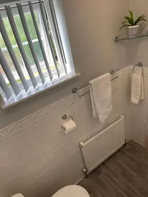 a bathroom with a toilet and a window and towels at Peaceful 3 Bed Home in Basildon