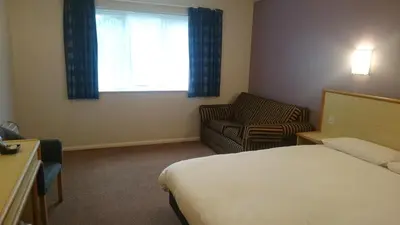 a hotel room with a bed and a chair and a window at Redwings Lodge Baldock in Baldock