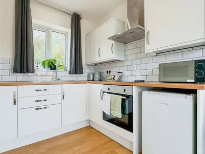 a white kitchen with white cabinets and a window at Badger Lodge - Uk30603 in Pidley