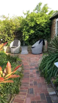 three chairs sitting on a brick path in a garden at The Blue Cow in Fenstanton