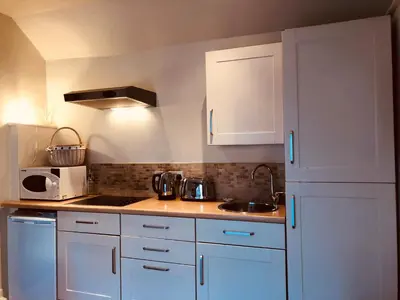 a kitchen with white cabinets and a sink and a microwave at The Blue Cow in Fenstanton