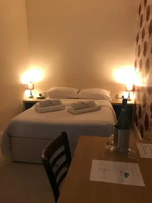 a bedroom with a bed and a table and two lamps at The Harp Freehouse and Guesthouse in Ipswich