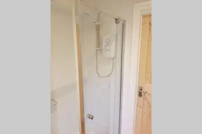 a shower with a glass door in a bathroom at Cosy, self contained annex in Cambridge
