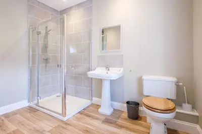 a bathroom with a shower and a toilet and a sink at The Dower Cottage in Sizewell