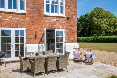 a patio with a table and chairs in front of a brick building at The Dower House in Sizewell