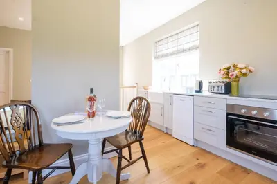 a white kitchen with a white table and chairs at The Dower Retreat in Sizewell