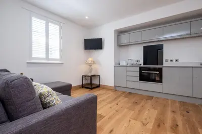 a living room with a couch and a kitchen at Three Tuns Apartments - Hazel - Aldeburgh Coastal Cottages in Pettistree