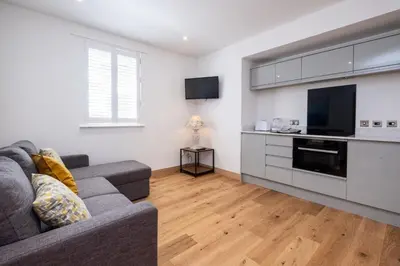 a living room with a couch and a kitchen at Three Tuns Apartments - Hazel - Aldeburgh Coastal Cottages in Pettistree